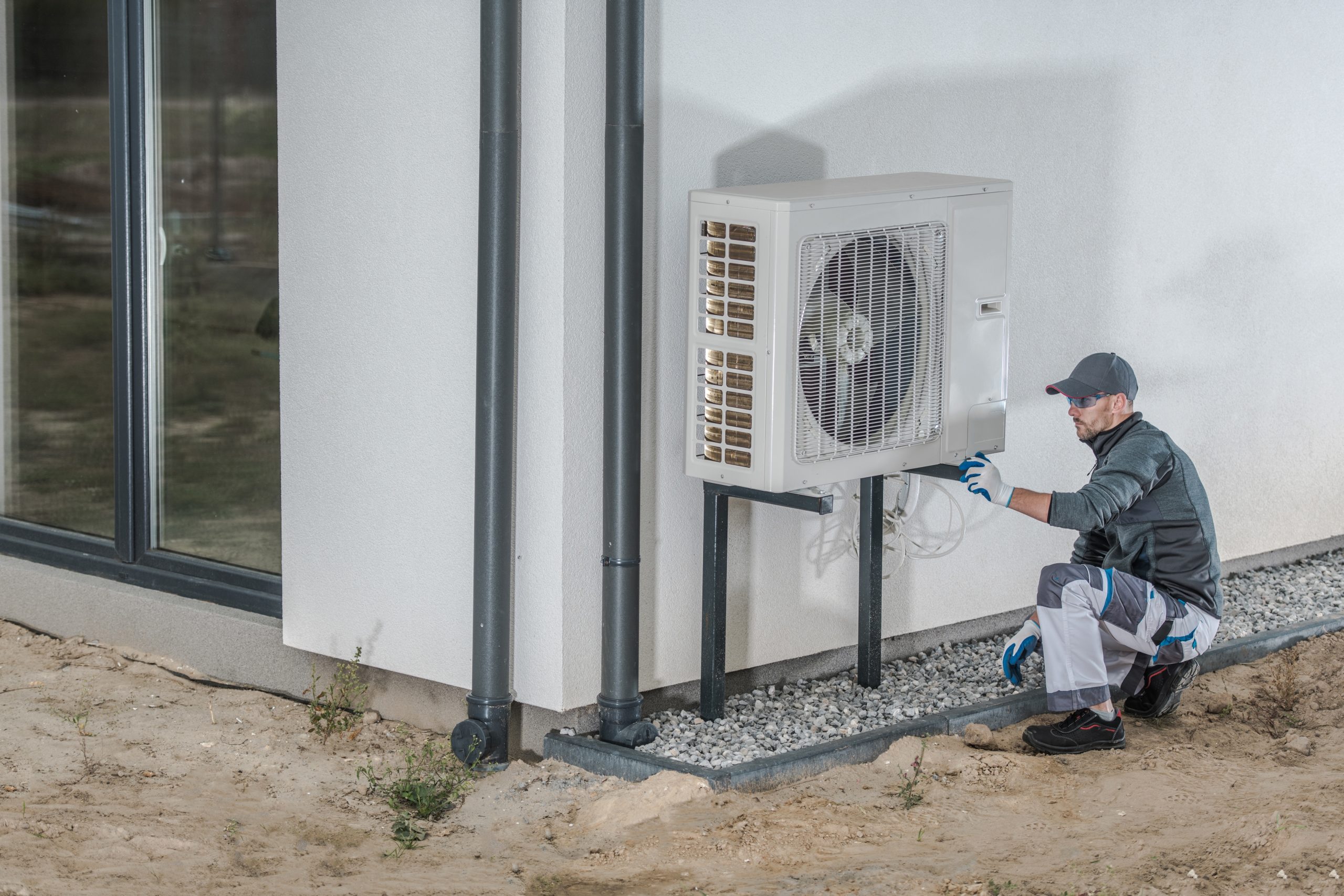 Heat Pump Installation Project. Caucasian Heating and Cooling Technician Installing New Device.