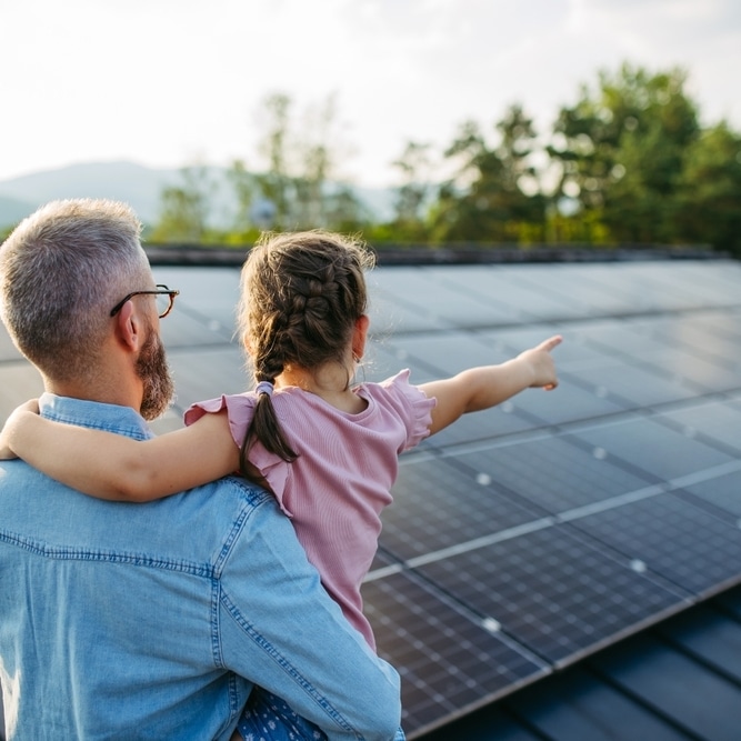 Panneaux solaires résidentiels : une énergie pour demain Père et fille observant une installation de panneaux solaires sur un toit de maison.